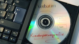 Diskette mit der Aufschrift "Kinderpornografie" in einem Laptop-Laufwerk 