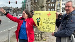 Pflegekräfte warnen in Recklinghausen mit einem Schild, auf dem "Diagnose: Pflegenotstand" steht, vor einem Kollaps in der Pflege: 