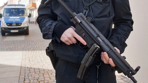 Polizist mit Maschinenpistole MP5 vor einem Körper