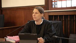 Lisa Grüter mit schwarzer Kleidung sitzt vor Aktenordner und Ipad im Gerichtssaal.