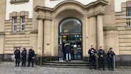 Bewaffnete Polizisten stehen links und rechts neben dem Eingang in ein altes Gerichtsgebäude