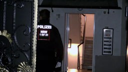 Ein Polizist löuft auf den Eingang des durchsuchten Mehrfamilienhauses in Bochum zu.