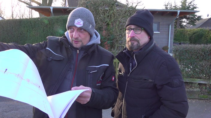 Daniel Liebendahl und Dirk Lieker gucken auf den Lageplan des Hauses