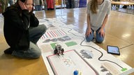 Schülerinnen schauen ihrem Lego-Roboter bei der Arbeit zu