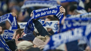 Fußballfans halten Schalke-Schals hoch