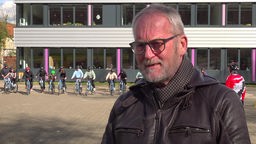 Reinhold Bauhus, ein Mann mit Brille, vor einem Schulgebäude