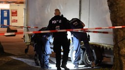 Polizisten suchen mit einer Taschenlampe nach Spuren