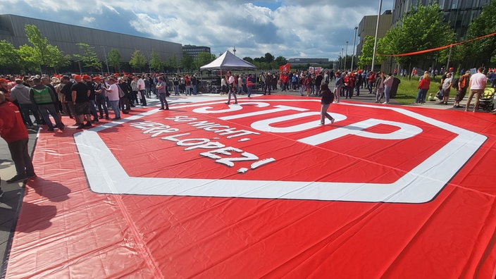 Vor der Thyssenkrupp-Hauptverwaltung in Essen haben Mitarbeiter ein riesiges rotes Plakat mit der Aufschrift "Stop, so nicht, Herr Lopez" ausgelegt