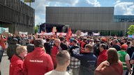 Vor der Thyssenkrupp-Hauptverwaltung in Essen protestieren am Donnerstag tausende Mitarbeiter, sie stehen mit Fahnen und Plakaten vor einer Bühne