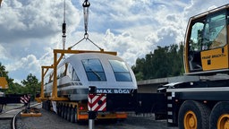 Das Zugabteil des Transrapid wird von einem Hubkran verladen