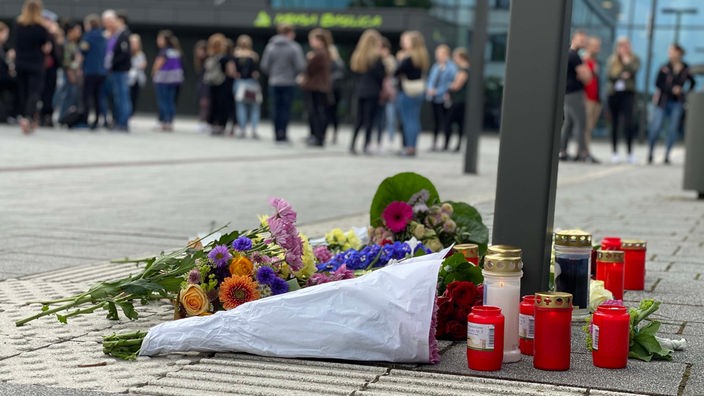 Blumen und Kerzen liegen auf dem Campus, Menschen gedenken still 