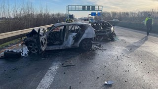 Zwei ausgebrannte Autos stehen auf einer Autobahn