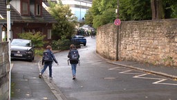 Zwei Kinder mit Schulranzen laufen in Richtung Schule