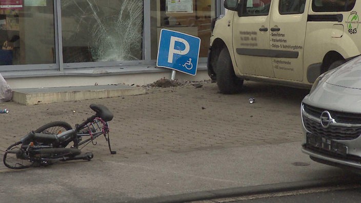 kleiner Platz mit zerstörter Glasscheibe und zerquetschtem Fahrrad