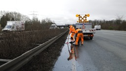 Griese und sein Kollege säubern den Ablauf von Wasser am Rand der Autobahn