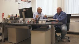 Zwei Herren, Uwe Sova und Jörg Nadler, sitzen an einem Schreibtisch