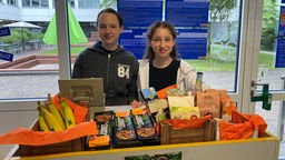 Zwei Schülerinnen verkaufen Fair-Trade-Produkte in ihrer Schule.