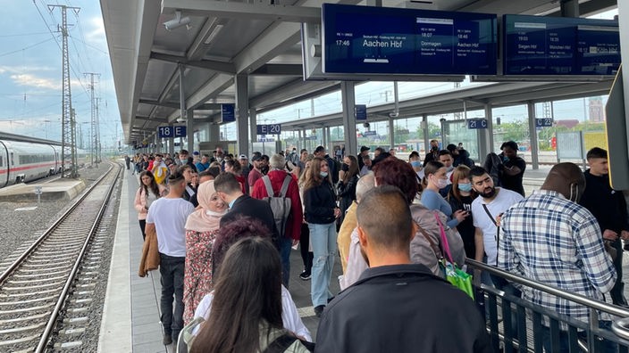 Viele Menschen warten in Dortmund am Bahnsteig auf einen einfahrenden Zug