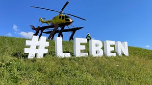 Der Schriftzug #LEBEN auf der Wiese, im Hintergrund der Hubschrauber am Kamener Kreuz