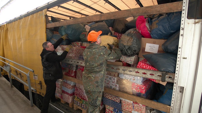 Helfer laden Hilfsgüter in einen LKW