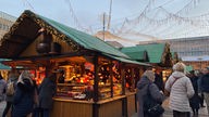 Besucher schlendern an Buden auf dem  Weihnachtsmarkt vorbei