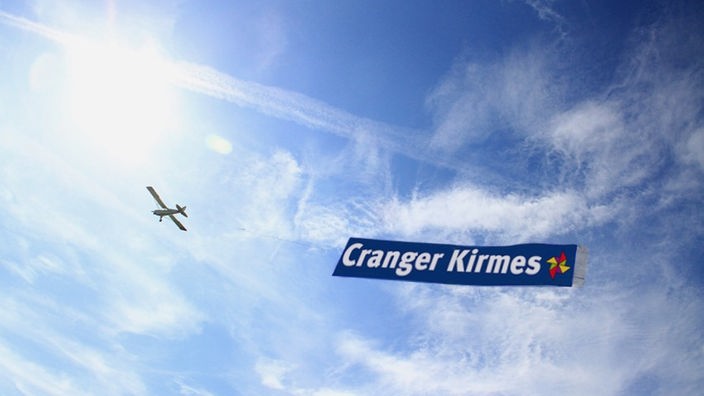 Bildmontage: Flugzeug zieht Werbebanner für die Cranger Kirmes