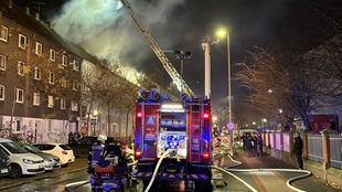 Feuerwehrmann bekämpft auf Leiter Dachstuhlbrand