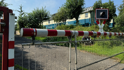 Eisenbahnwaggons hinter einer geschlossenen Schranke