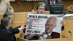 Saaldiener nehmen am 25.03.2010 in Düsseldorf im Landtag dem fraktionslosen Abgeordneten Rüdiger Sagel (Die Linke) ein Plakat weg.