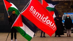 Samidoun-Mitglieder schwenken große Fahnen