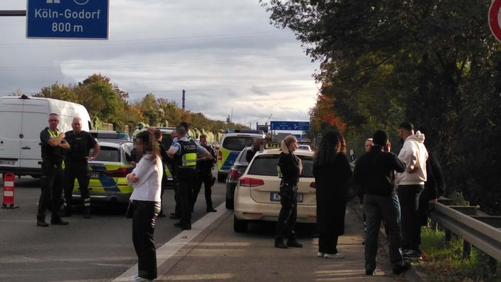 Menschen stehen nach einer Schlägerei beim Polizeieinsatz auf dem Standstreifen an der A555
