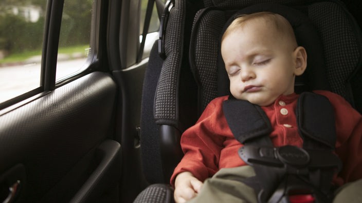 Ein Baby schläft in einem Auto im Kindersitz