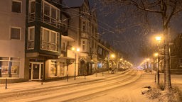 Eine beleuchtete Straße in Solingen ist verschneit