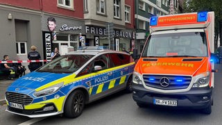 Ein Einsatzfahrzeug der Polizei und ein Rettungswagen der Feuerwehr stehen vor einem Friseursalon in Hagen.