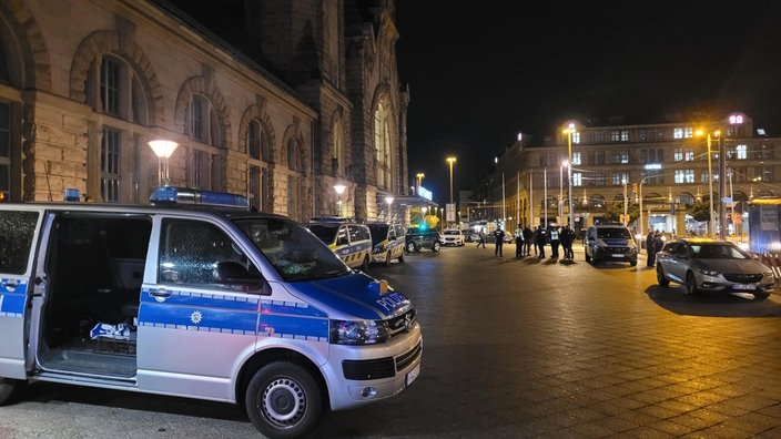 Nach den Schüssen der Polizei auf ein Krefelder Kino stehen ein Polizeiauto und Polizisten vor dem Bahnhof