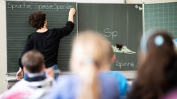 Schulunterricht: Eine Lehrerin schreibt etwas an die Tafel