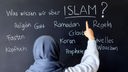 Eine muslimische Schülerin vor einer Tafel mit Begriffen aus dem Islam im Islamunterricht