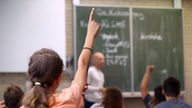 ARCHIV - Eine Schülerin hebt  im Unterricht an einer Schule  den Finger. 