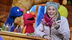Singa Gätgens, Moderatorin des "KiKA-Baumhaus" und die Sesamstraßen-Figuren Grobi (l) und Elmo stehen bei einem Settermin bei Dreharbeiten in einem Studio des MDR Landesfunkhaus Thüringen.
