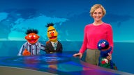 Caren Miosga, Moderatorin der «Tagesthemen», steht mit Ernie (im Pyjama, l-r), Bert (mit Krawatte) und Grobi (als Putzfrau) in der Kulisse der ARD-Nachrichtensendung. 