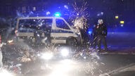 31.12.2022, Berlin: Polizeibeamte stehen hinter explodierendem Feuerwerk