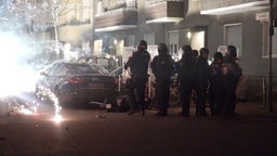31.12.2022, Berlin: Polizeibeamte stehen hinter explodierendem Feuerwerk