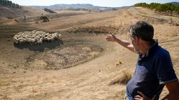 Schäfer zeigt auf einen ausgetrockneten Teich neben seiner Farm