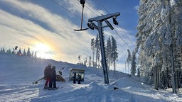 Skifahrer fahren in einem Schlepplift eine Piste hoch