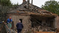 Slowjansk, Ukraine: Menschen entfernen Trümmer aus einem beschädigten Haus nach einem nächtlichen russischen Beschuss