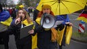 Demonstrierende in Farben der Ukraine mit einem Megaphon