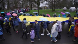 Demonstrierende mit einer großen Ukraine-Flagge