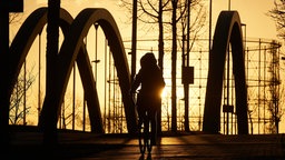 Eine Radfahrerin fährt am Dortmund-Ems-Kanal in Münster über eine Brücke.