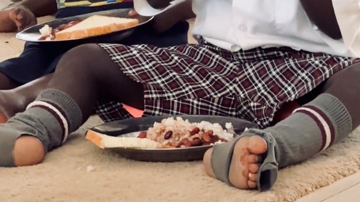 Ein Kind mit kaputten Socken sitzt vor Essen