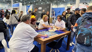 Messebesucher spielen Brettspiel 